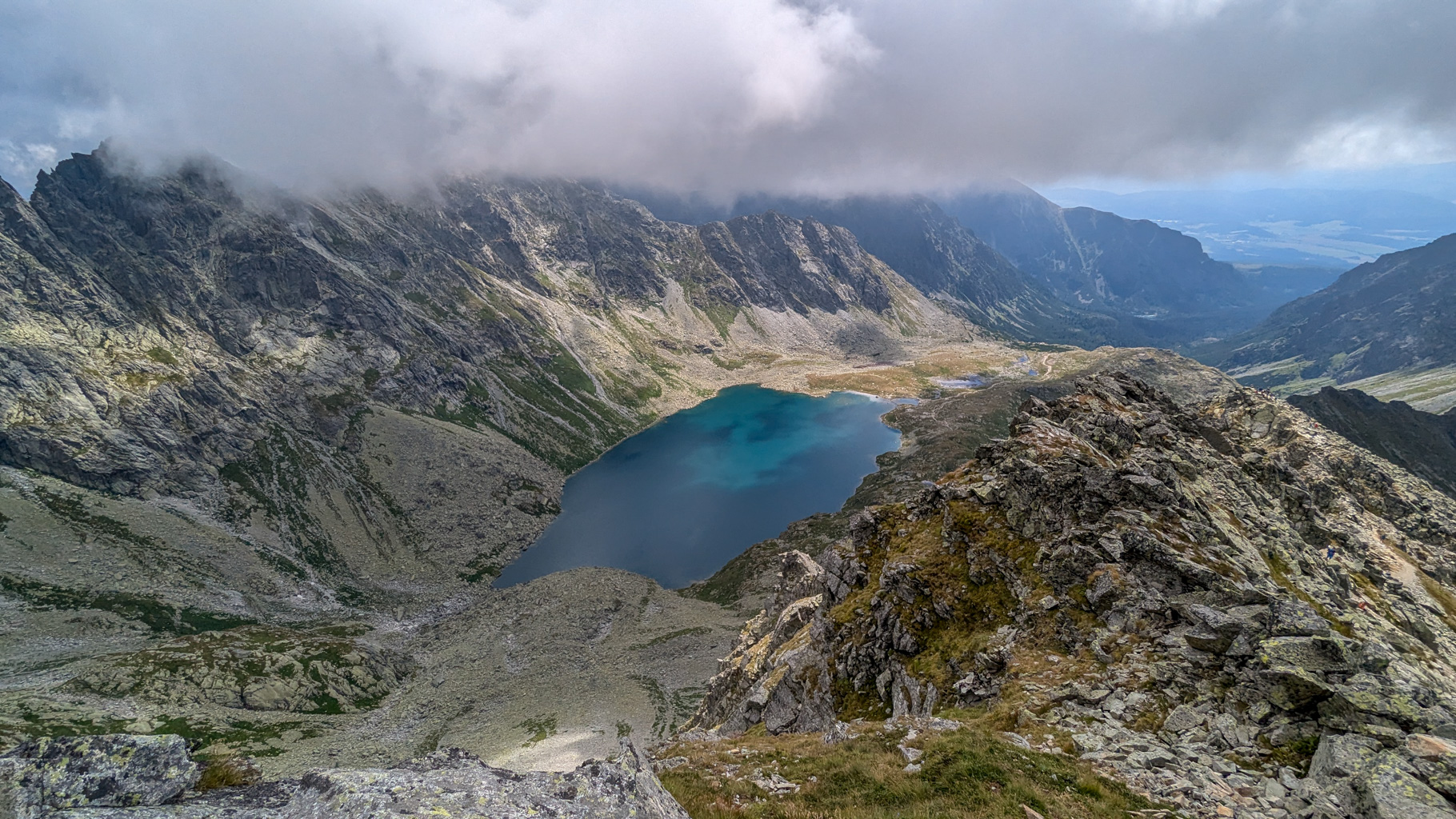 Výhľad z Kôprovského štítu do Mengusovskej doliny, kde dominuje Veľké Hincovo pleso a v pozadí Mengusovské štíty zahalené v oblakoch.