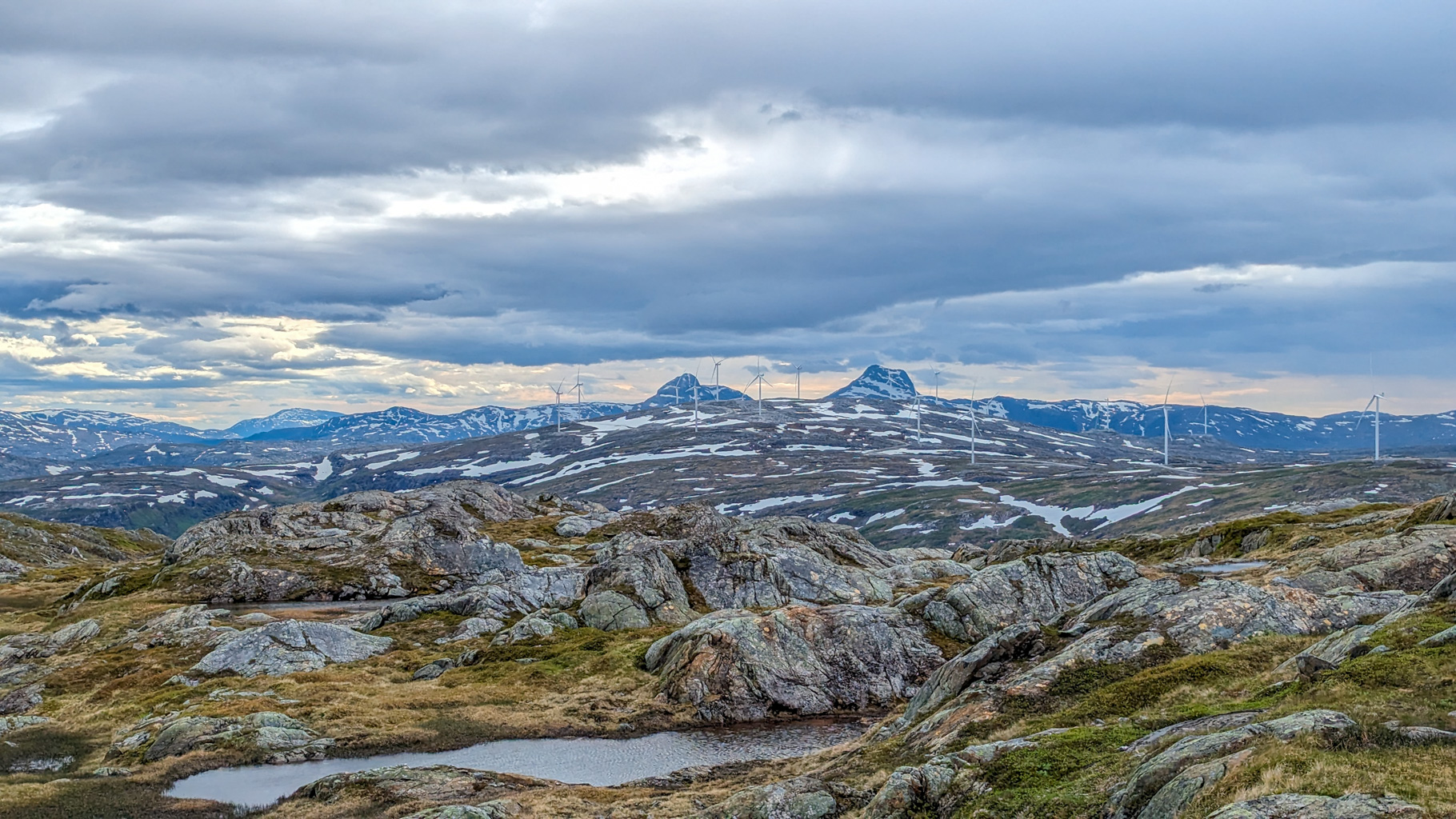 Panoráma s výhľadom na okolité hory, údolia a veterný park neďaleko vrcholu Øyfjellvarden.