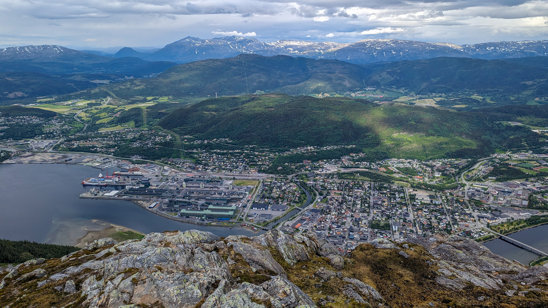 Pohľad z Øyfjellvarden na Mosjøen, jeho prístav, rieku Vefsna a zasnežené pohoria regiónu Helgeland.