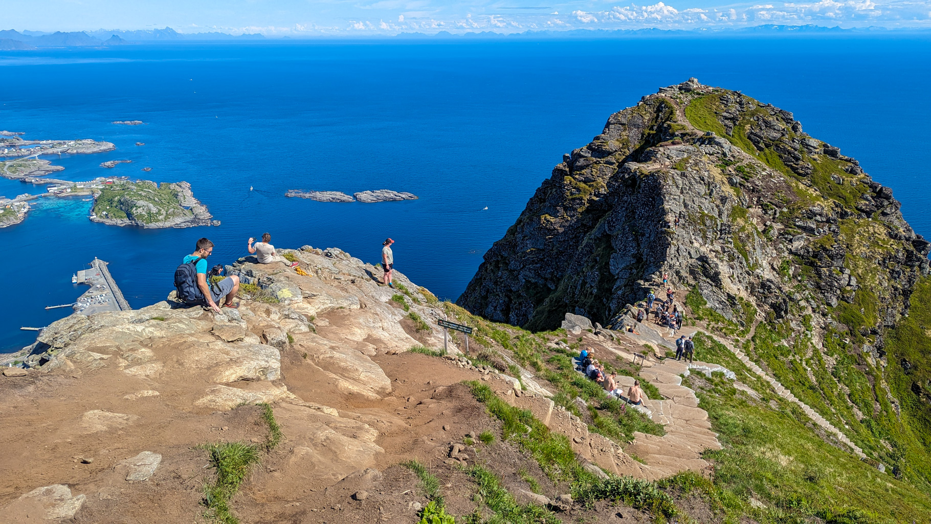 Vrcholová časť Reinebringen s turistami obdivujúcimi výhľad na Vestfjord.