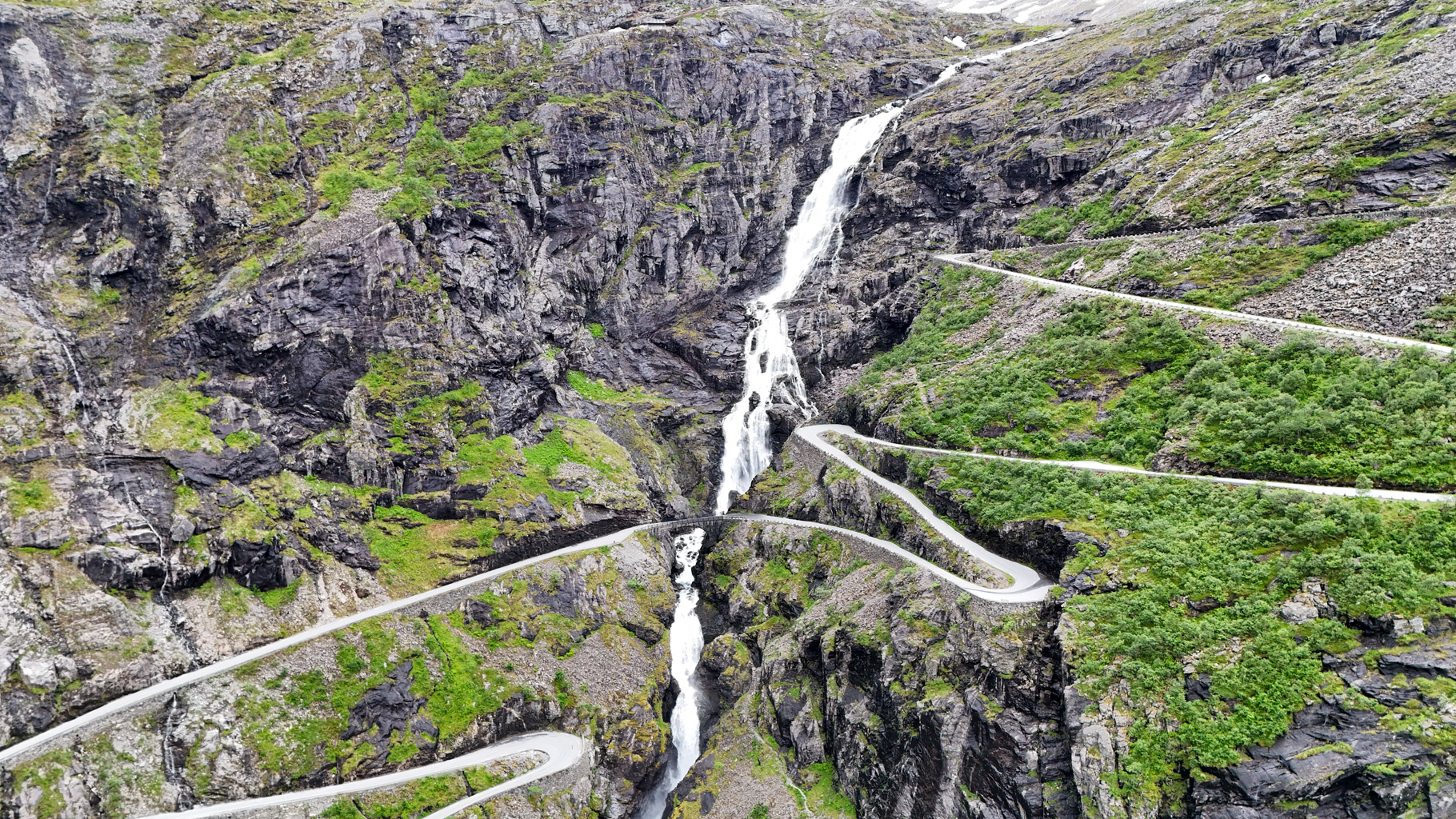 Pohľad na serpentíny Trollstigen a tok vodopádu Stigfossen uprostred údolia.