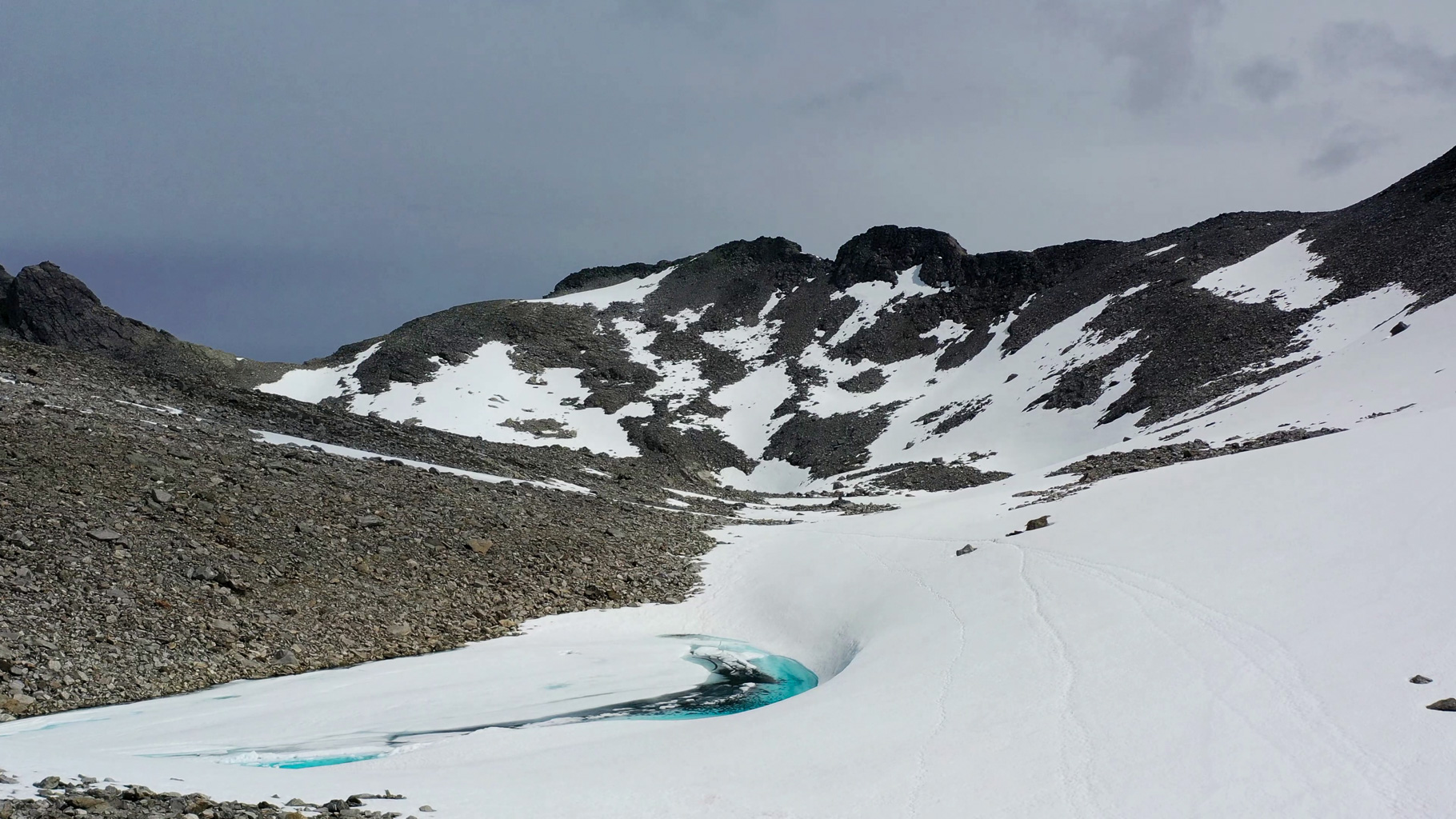 Na obzore sa črtá sedlo Stabbeskaret (1420 m n. m.). Cesta vedie cez sneh, stopy miznú, ale cieľ je blízko.