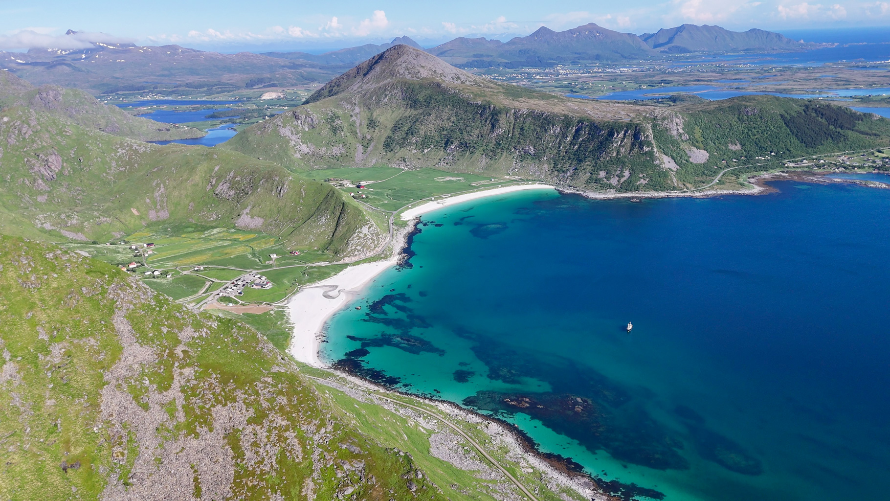 Pohľad smerom k pláži Hauklandstranda a široké panorámy z Veggenu. Haukland patrí k najobľúbenejším miestam na kúpanie na Lofotách.