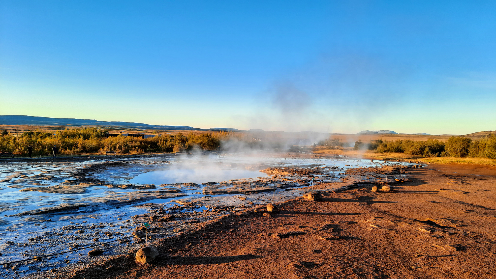 Gejzír Strokkur. Ku gejzírom sa oplatí prísť skoro ráno. Predtým, ako dorazia autobusy turistov.