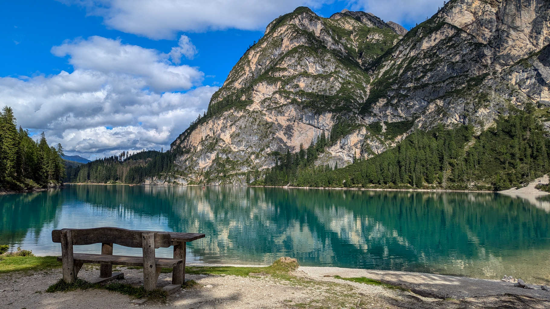 Drevená lavička pri Lago di Braies poskytuje nádherný výhľad na pokojné vody jazera a zrkadliace sa hory.