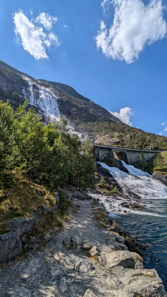 Vyústenie vodopádu Langfoss do Åkrafjordu pod cestou E134. Voda preteká pod mostom a priamo ústi do fjordu na konci skalného svahu.