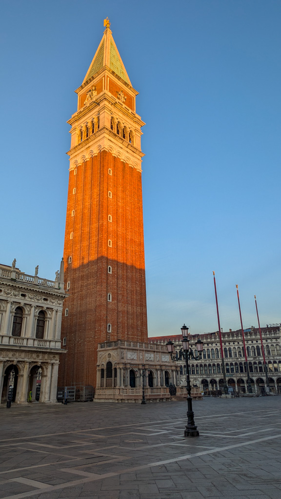 Ranné slnko osvetľuje zvonicu Campanile di San Marco v Benátkach, ktorá je najvyššou stavbou mesta a
            symbolom jeho histórie.
        